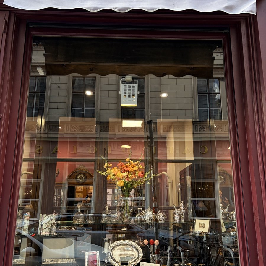 Schaufenster von Otto Feiler mit Silberwaren und Blumen hinter weinrotem Rahmen