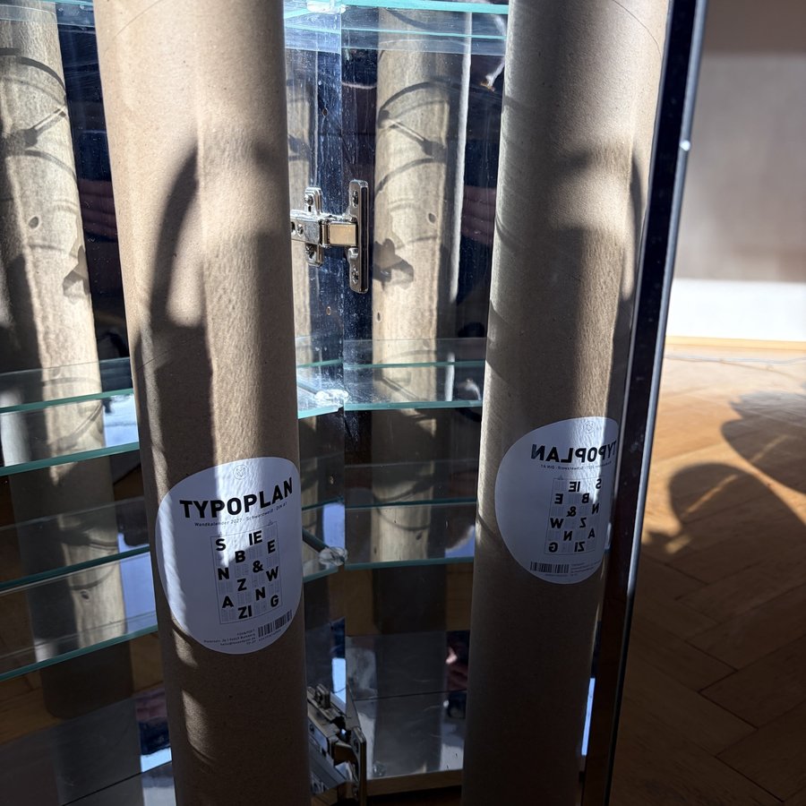 Zwei Kartonrollen mit Typoplan-Etikett in einer Glasvitrine
